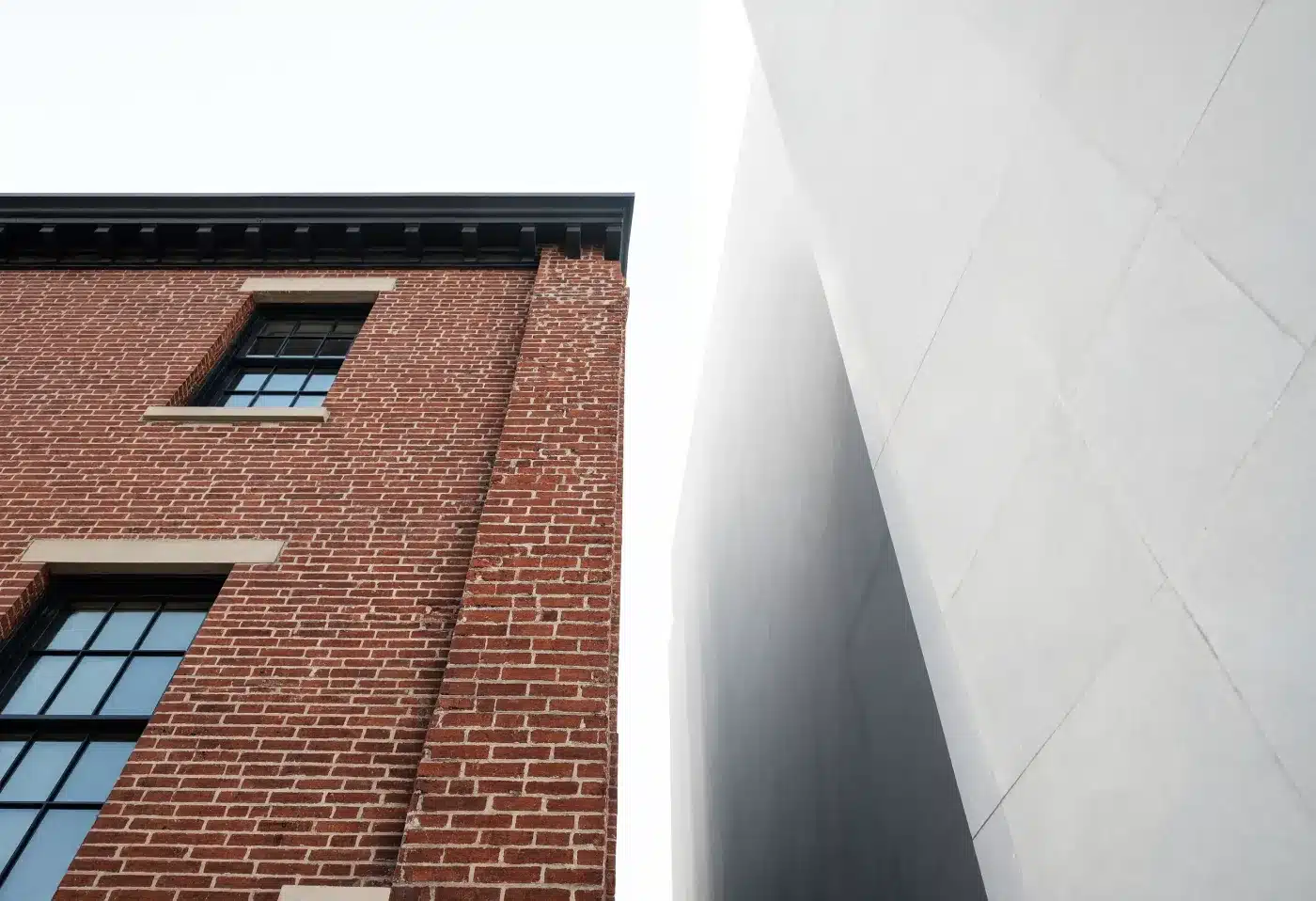 A party wall between a low historic brick building and the blank flank of a taller modern tower
