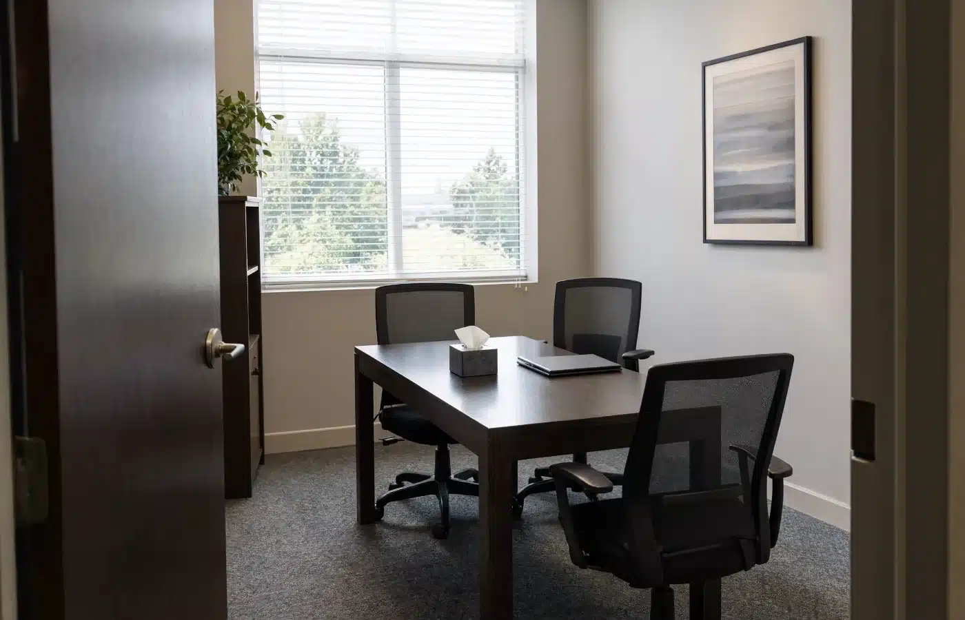 An empty mediator’s office with two chairs on one side of the table and one on the other