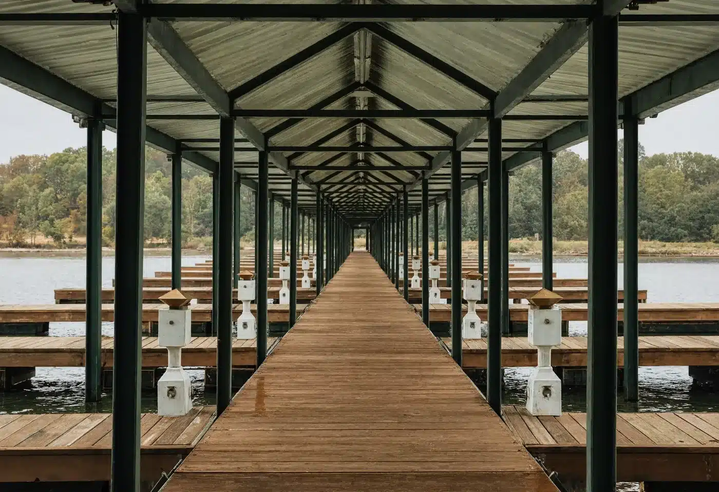 A covered dockominium walkway with empty berths and utility pedestals on both sides