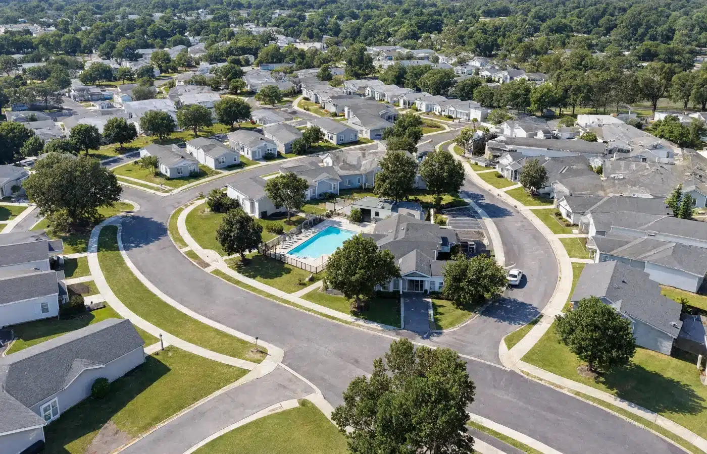 Aerial view of a manufactured home community with curving streets, a clubhouse and a community pool
